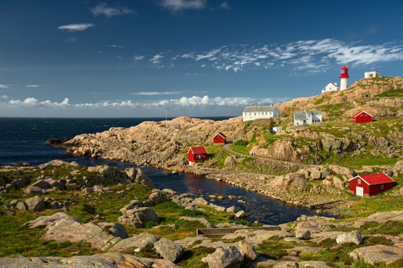 Rocky coast near Lindesnes with the lighthouse in the background Rocky coast near Lindesnes with the lighthouse in the background