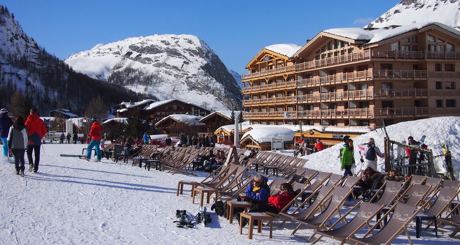 people relaxing in deck chairs outside a ski bar